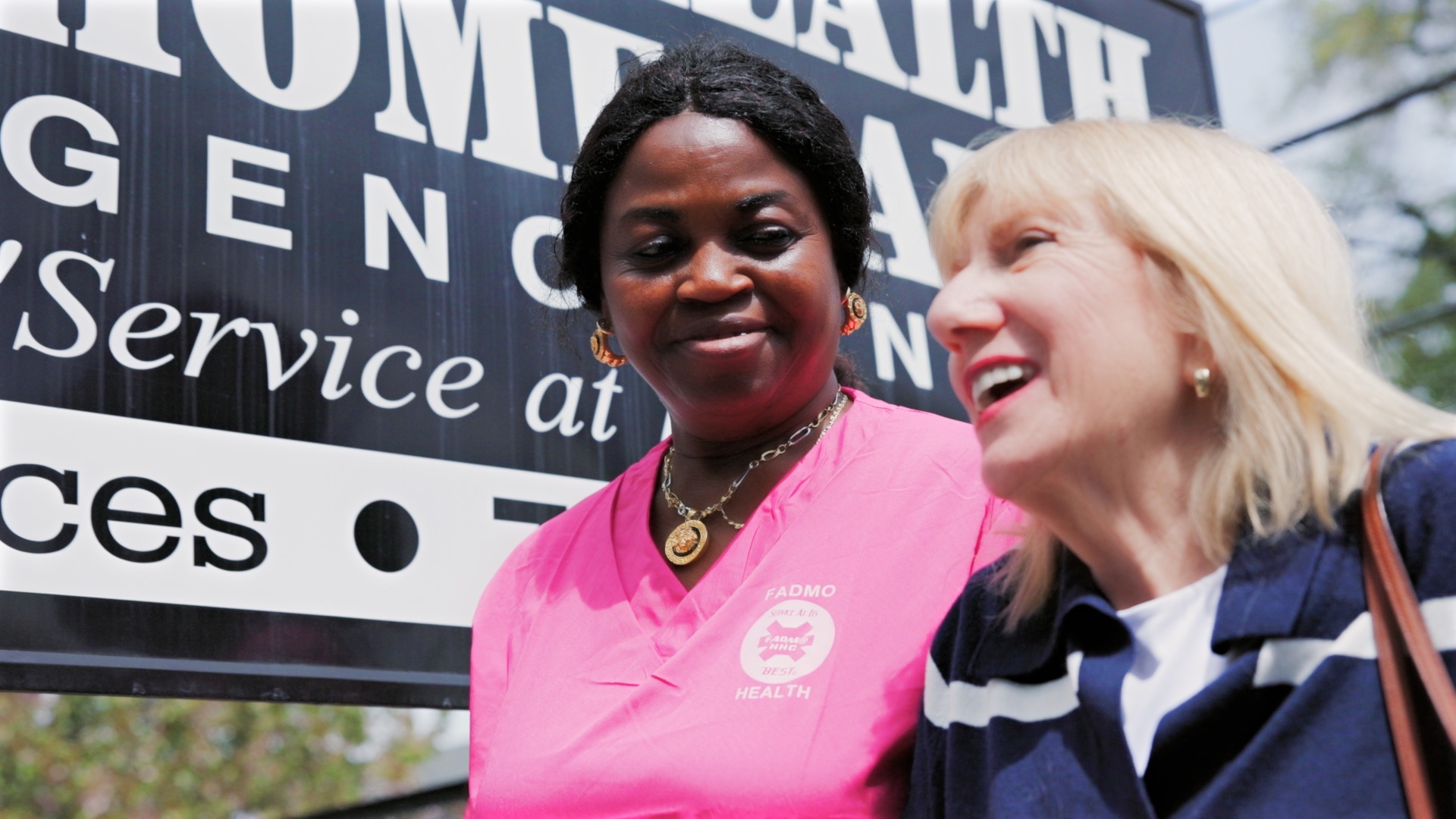 FADMO caregiver and client laughing together outside the agency sign